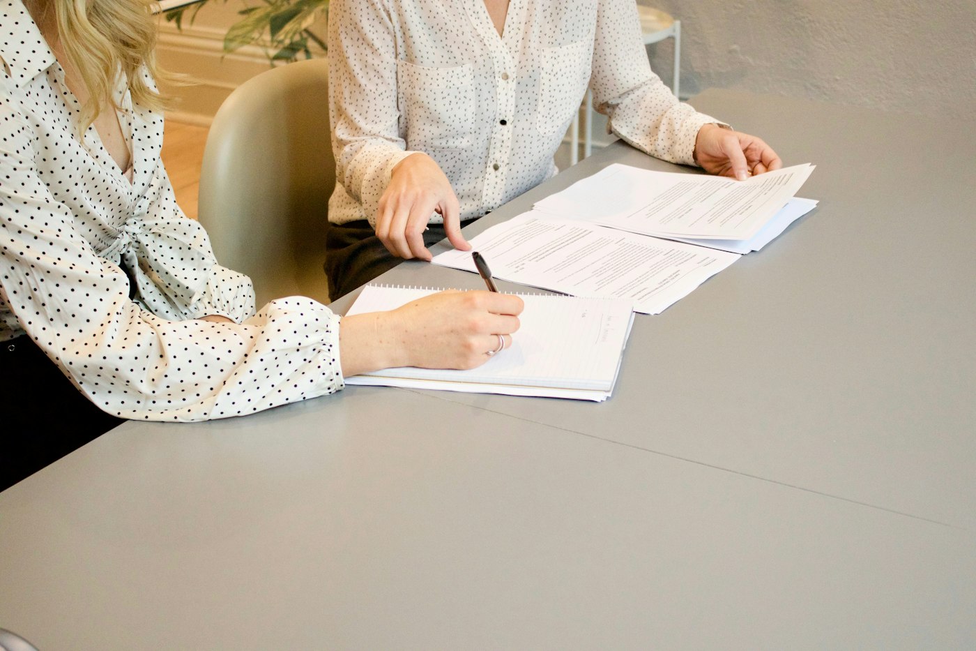 Two people reviewing and signing documents at a desk